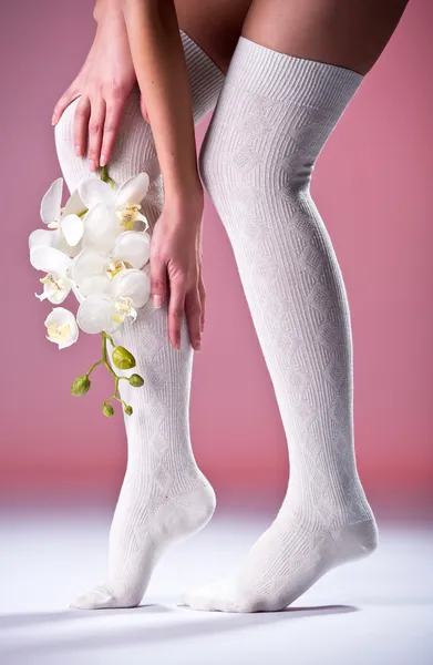 Beautiful woman legs with white orchid — Stock Photo, Image