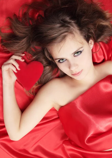 美丽的女孩躺在红色丝绸 — 图库照片