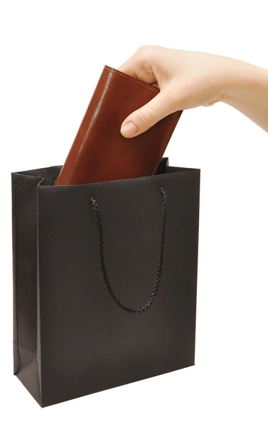 Mão soltando uma bolsa dentro de um saco preto — Fotografia de Stock