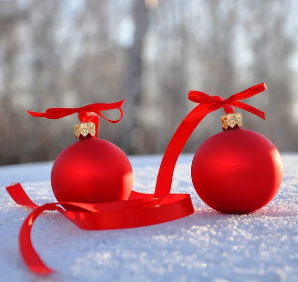 Kırmızı cam Noel topları arka plan karda — Stok fotoğraf