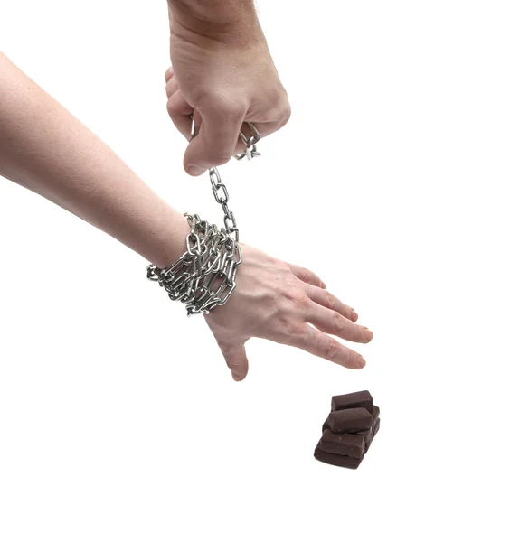 Woman's hand in chains reaching for candy — Stock Photo, Image