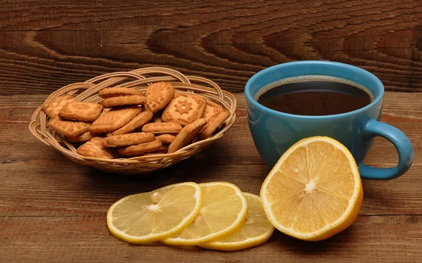 Xícara de chá com limão e biscoitos na cesta — Fotografia de Stock