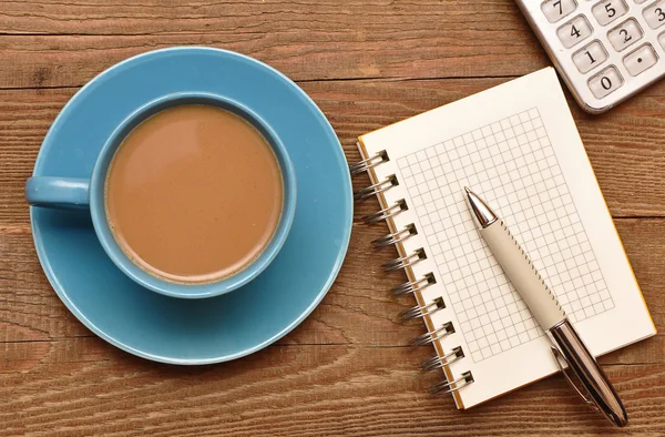 コーヒー カップ スパイラル ノートと古い木製テーブル上のペン — ストック写真