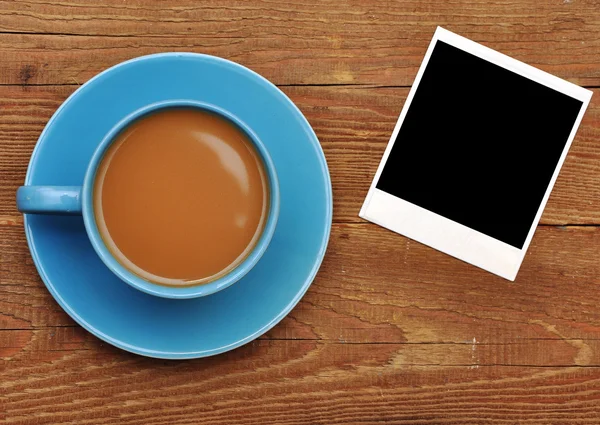 Blaue Tasse heißen Kaffee und alten Fotorahmen aus Papier — Stockfoto