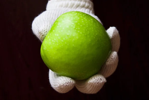 A hand in white glove holding an apple — Stok fotoğraf