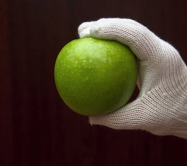 Une main en gant blanc tenant une pomme — Photo