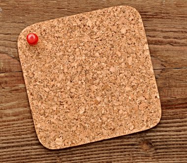 Cork texture pressed red pushpin on wood background