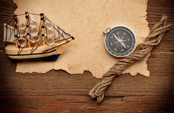 Papel velho, bússola, corda e modelo de barco clássico em backgrou de madeira — Fotografia de Stock