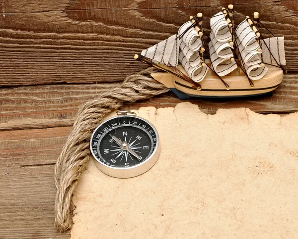 Papel velho, bússola e modelo de barco clássico em fundo de madeira — Fotografia de Stock