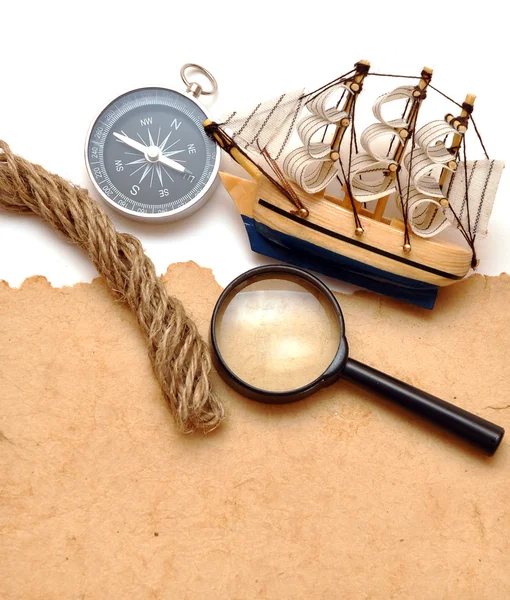在旧的纸上的绳索 放大镜 指南针和模型经典船 — 图库照片