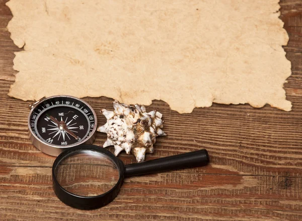 Old paper, compass and magnifying glass on wood background — Stock Photo, Image