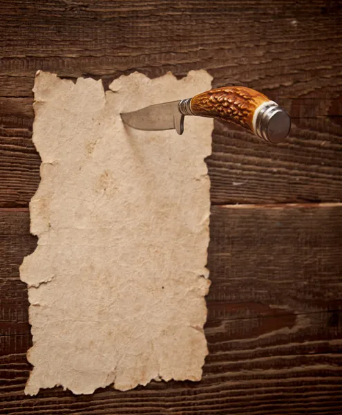 Oud papier vastgemaakt aan een houten muur met een mes — Stockfoto