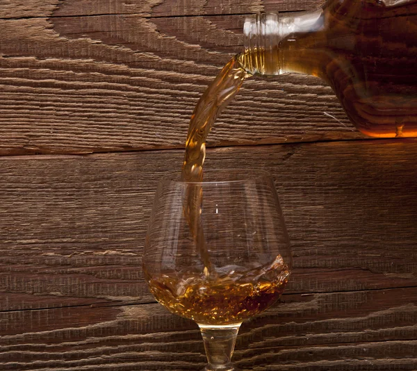Verser le cognac d'une bouteille dans un verre — Photo