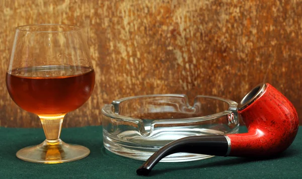 Труба и стакан алкоголя на зеленом войлоке — стоковое фото