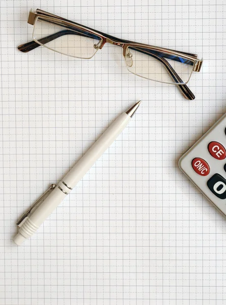 Ручка, очки и калькулятор на рабочей бумаге — стоковое фото
