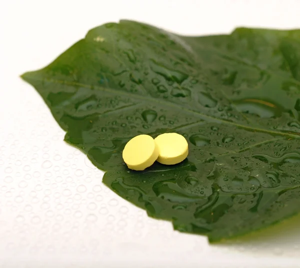 Pilule jaune sur une feuille verte humide — Photo