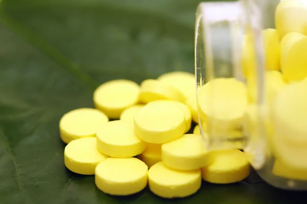 Comprimido amarelo sobre uma folha verde — Fotografia de Stock