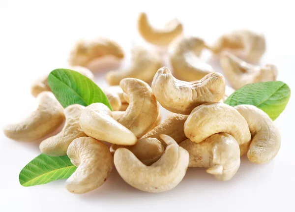 Mogna cashewnötter med blad på en vit bakgrund. — Stockfoto