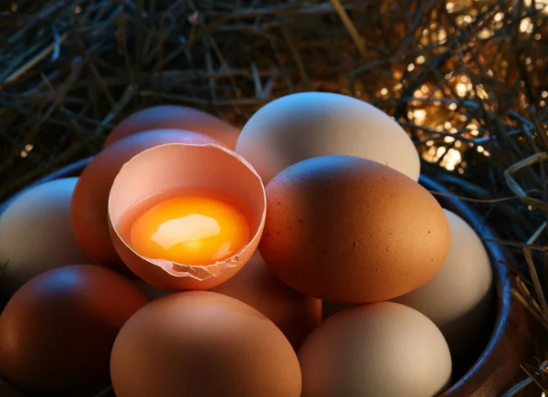 Huevos de pollo en la paja con medio huevo roto a la luz de la mañana . —  Fotos de Stock