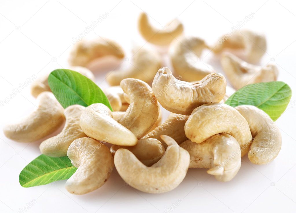 Ripe cashew nuts with leaves on a white background.