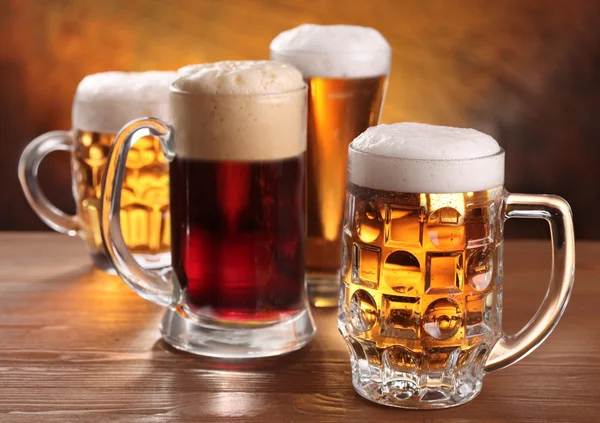 Cool beer mugs over wooden table. — Stock Photo, Image