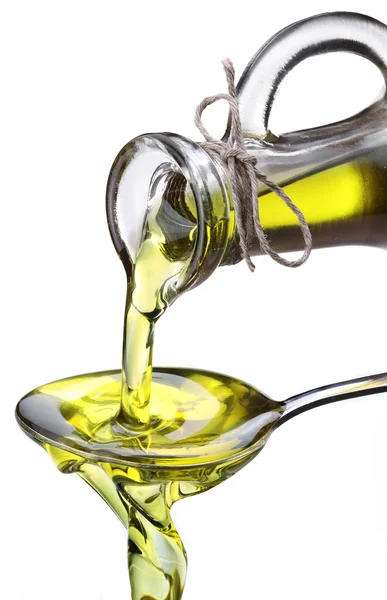 Olive oil flowing from carafe into the spoon. — Stock Photo, Image
