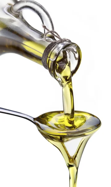Olivový olej teče z karafy do lžíce. — Stock fotografie