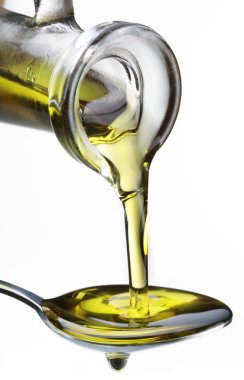 Olive oil flowing from carafe into the spoon. clipart
