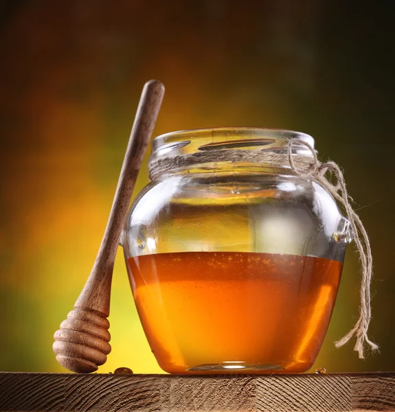 Hrnec medu a dřevěnou tyčí. — Stock fotografie