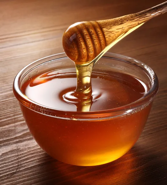 Honey pouring from drizzler into the bowl. — Stock Photo, Image