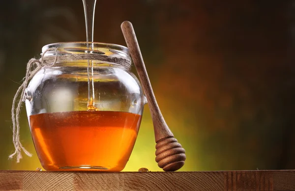Pot is being filled with honey and a drizzler. — Stock Photo, Image