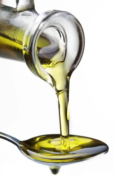 Оливковое масло, текущее из графина в ложку . — стоковое фото