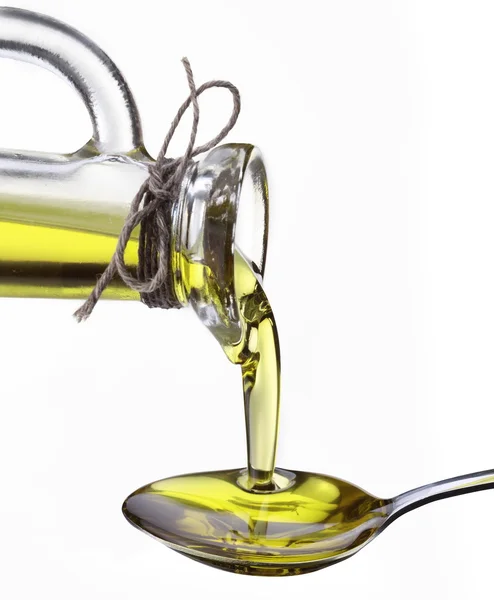 Olive oil flowing from carafe into the spoon. — Stock Photo, Image