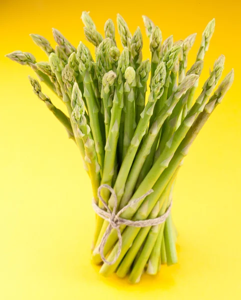 Sheaf of asparagus on a yellow background. — Stock Photo, Image