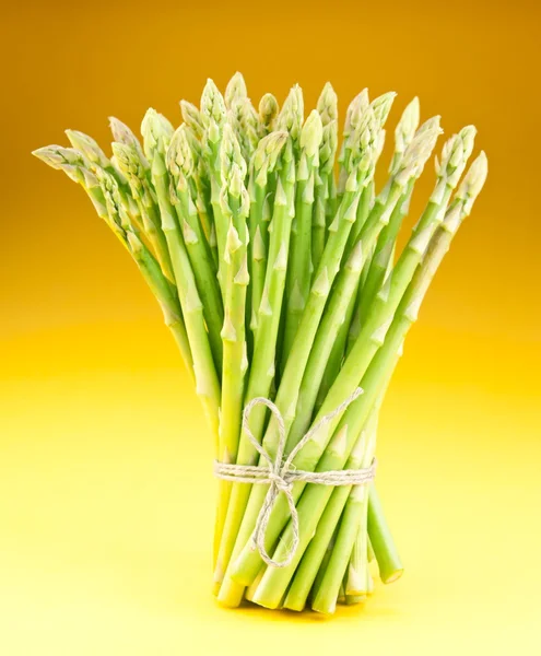 Sheaf of asparagus on a yellow background. — Stock Photo, Image