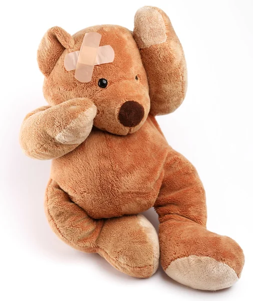 Ziek teddybeer met gips op zijn kop. geïsoleerd op een witte achtergrond. — Stockfoto