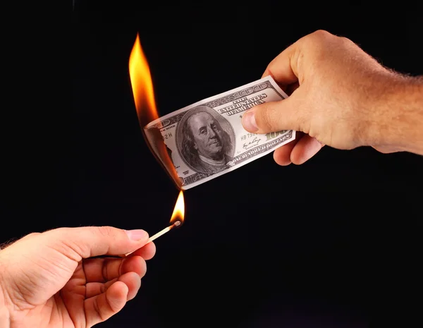 100 in hand, set fire to a match. Isolated on a black — Stock Photo, Image