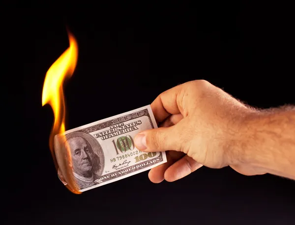 Un dollar brûlant à la main isolé sur un noir — Photo