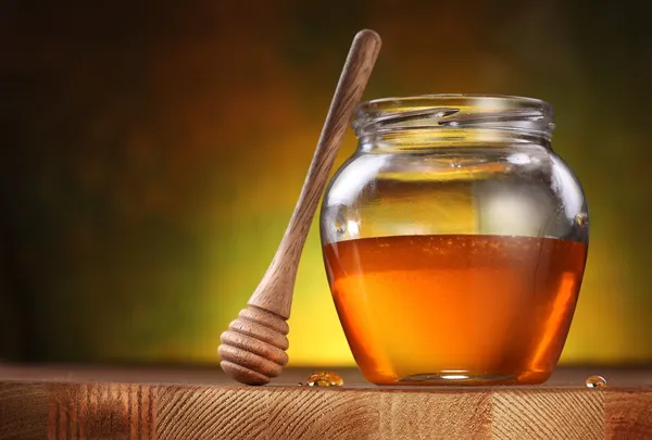 Pot of honey and wooden stick. — Stock Photo, Image
