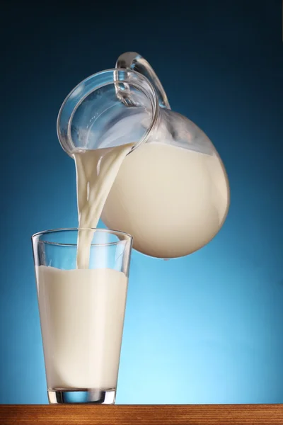 Milk pouring from jar into glass. — Stock Photo, Image