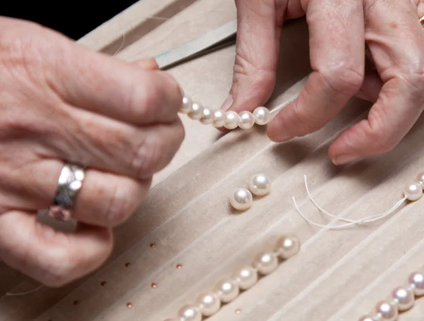 Sluit hand juwelier rijgen parels aan een ketting — Stockfoto