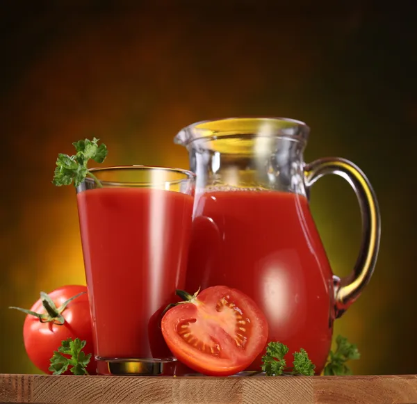Kruik en glas vol met tomatensap. — Stockfoto