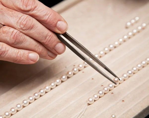 Sluit hand juwelier rijgen parels aan een ketting Stockfoto