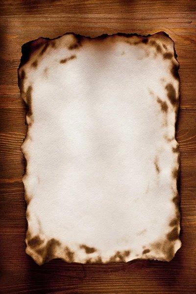 Queimado nas bordas de papel texturizado contra uma parede de madeira — Fotografia de Stock