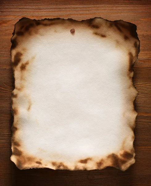 Verbrand op de randen geweven papier tegen een houten muur — Stockfoto