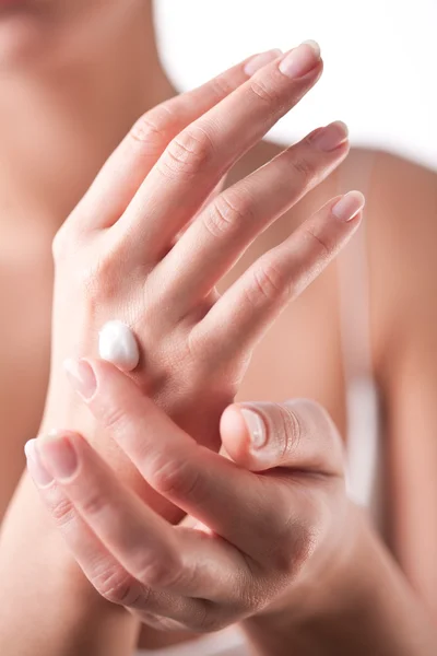 Smiling young woman applies cream on her hands. On a white backg — Stock Photo, Image