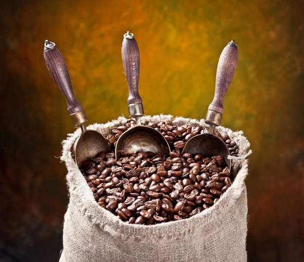 Розсип кавових зерен і совок. На темному тлі . — стокове фото