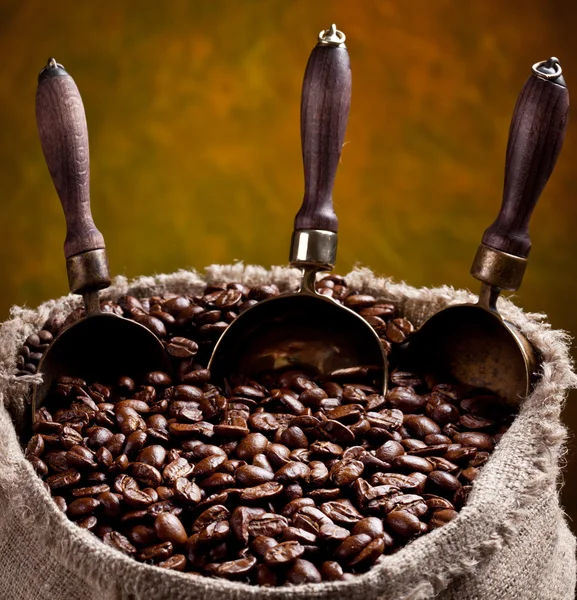 Розсип кавових зерен і совок. На темному тлі . — стокове фото