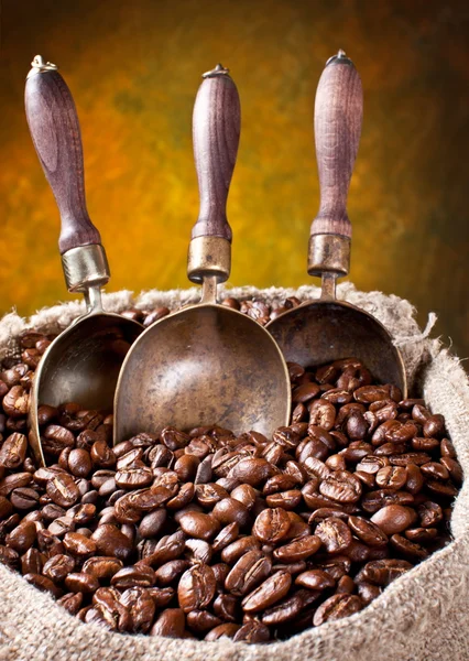 Säck kaffebönor och scoop. på en mörk bakgrund. — Stockfoto