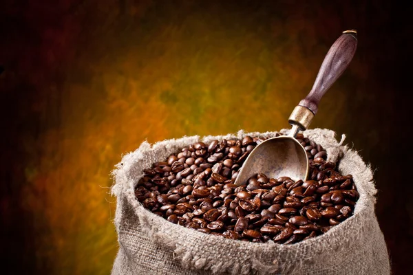 Plundering van koffiebonen en scoop. op een donkere achtergrond. — Stockfoto